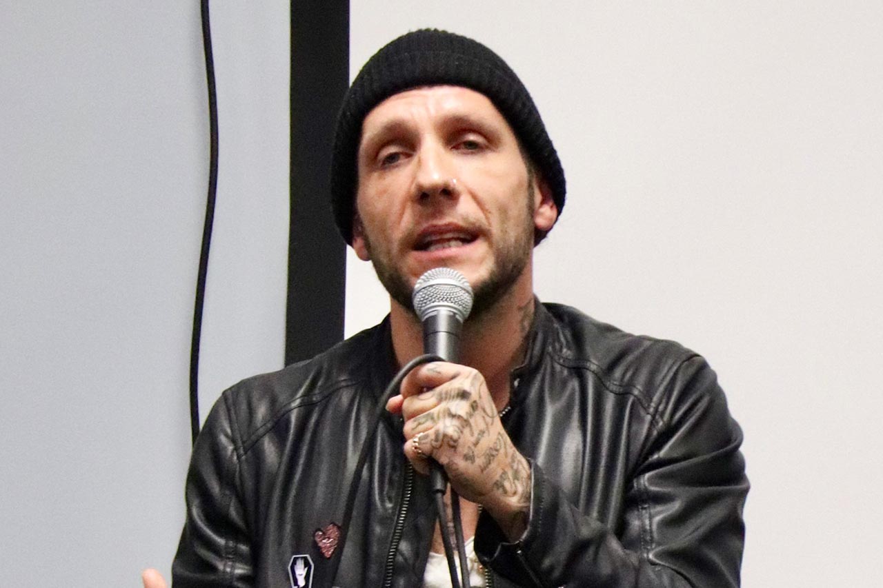 Brandon novak with a black leather jacket and a microphone
