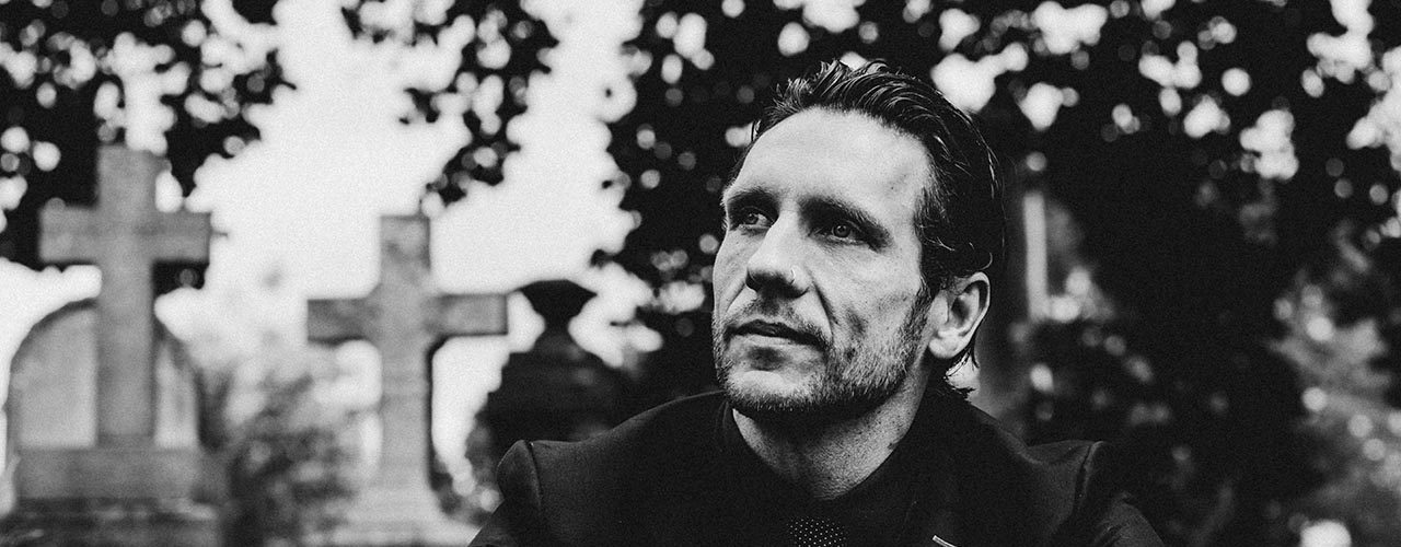 Brandon novak with a black suit in a graveyard